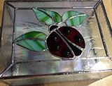 a box with a ladybug on the top of it, all made from stained glass
