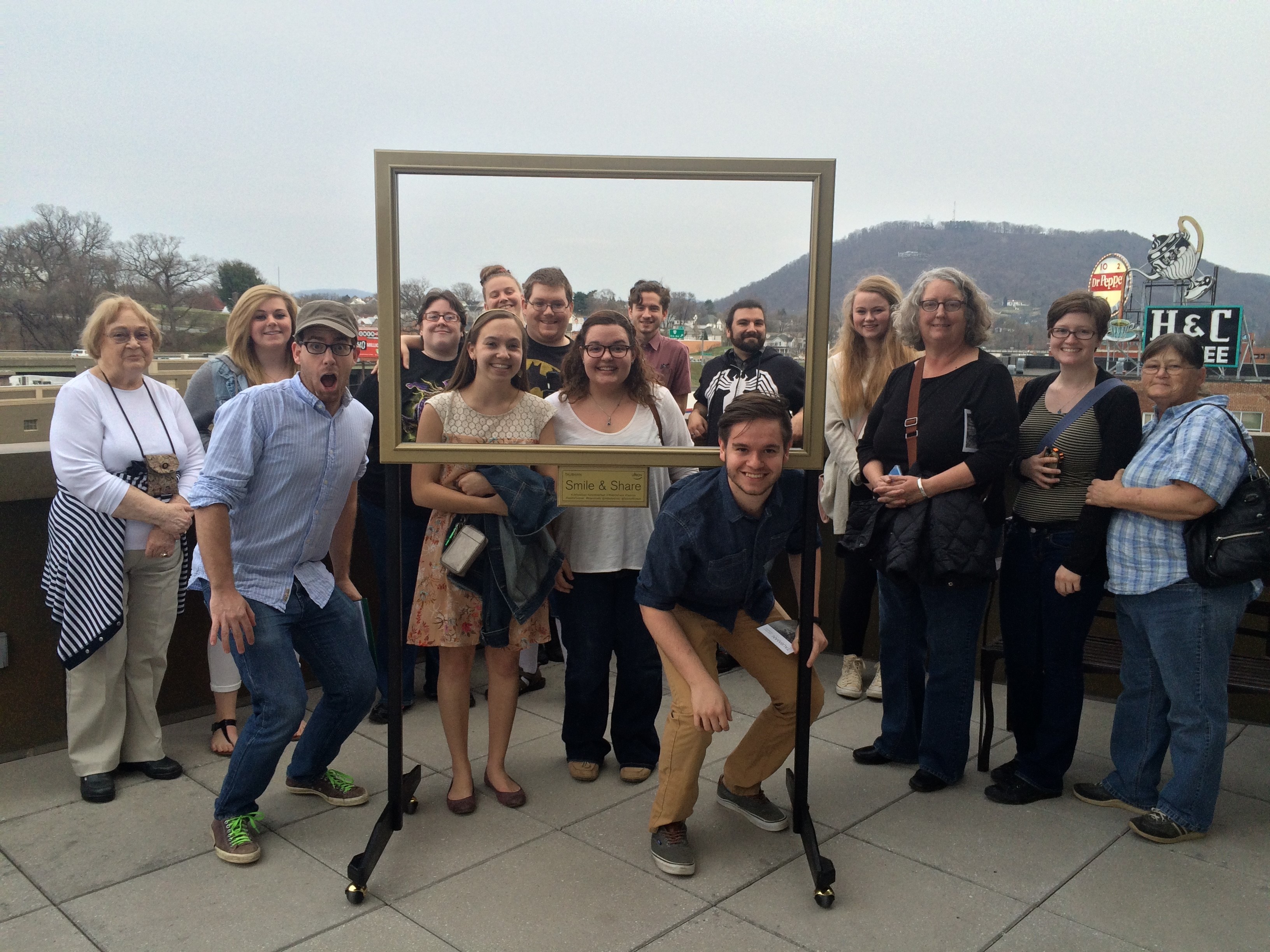 group of 15, faculty and students with empty picture frame in the middle at the Taubman Museum